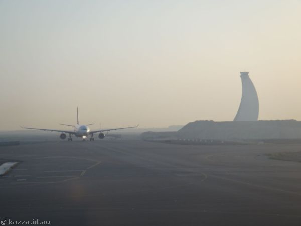 Aircraft and air traffic control tower in the sunrise haze at Abu Dhabi airport